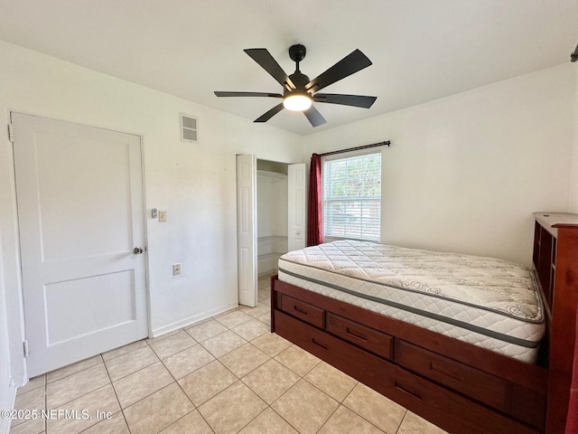 tiled bedroom with ceiling fan and a closet