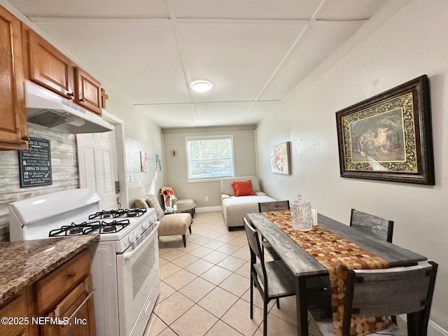 kitchen featuring dark stone countertops, gas range gas stove, and light tile patterned floors