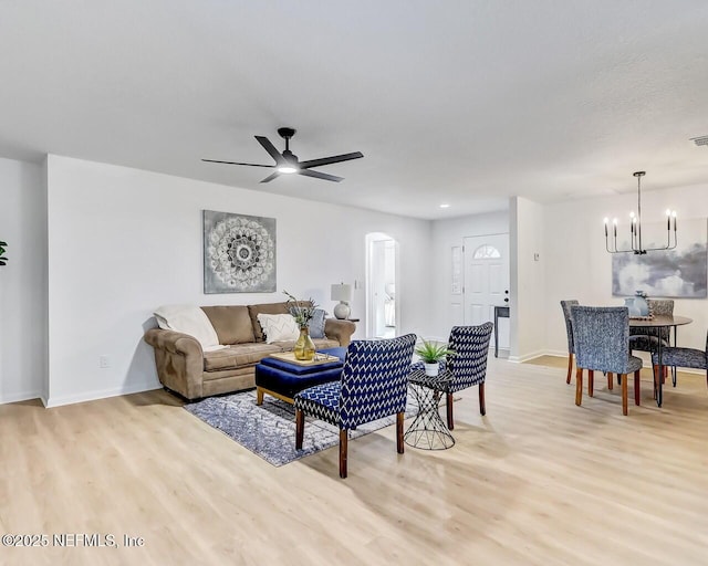 living room with ceiling fan with notable chandelier and light hardwood / wood-style flooring