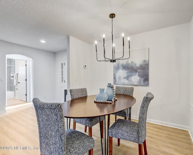 dining area featuring wood-type flooring, an inviting chandelier, and a textured ceiling