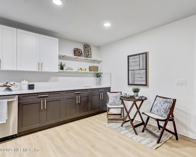 bar featuring stainless steel dishwasher, dark brown cabinetry, light hardwood / wood-style flooring, and white cabinets