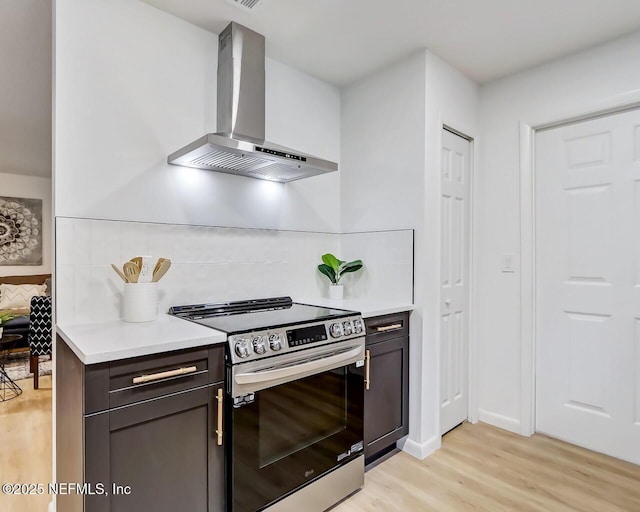 kitchen featuring exhaust hood, decorative backsplash, light hardwood / wood-style floors, and stainless steel electric range