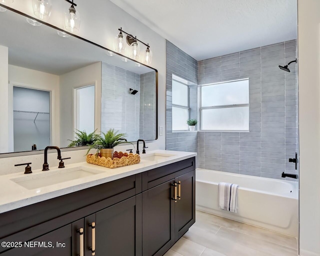 bathroom with tiled shower / bath combo, vanity, and tile patterned flooring