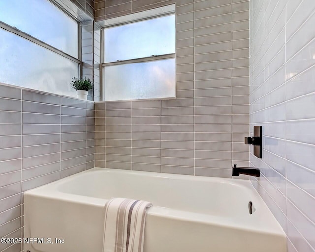 bathroom with tile walls and a washtub