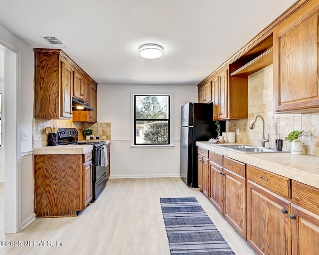 kitchen with sink, light hardwood / wood-style flooring, backsplash, and black appliances