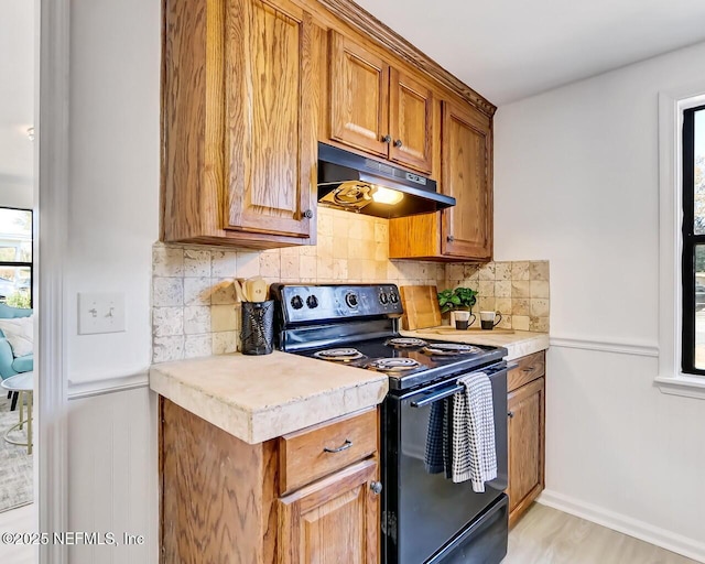 kitchen with black electric range, backsplash, and light hardwood / wood-style flooring