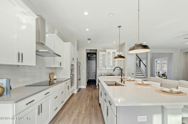 kitchen with sink, white cabinetry, black electric cooktop, pendant lighting, and wall chimney range hood