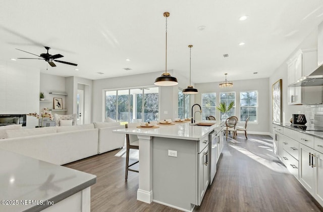 kitchen featuring white cabinetry, decorative light fixtures, sink, and a center island with sink