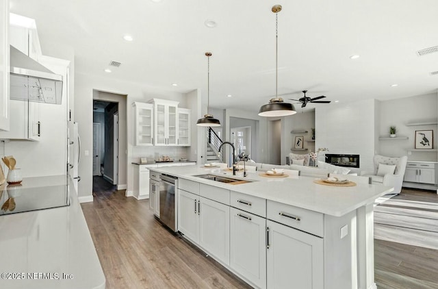 kitchen featuring white cabinetry, dishwasher, sink, and an island with sink