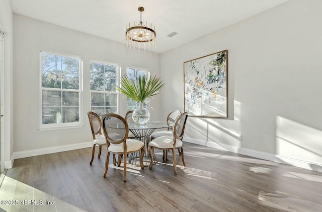 dining area featuring hardwood / wood-style flooring and an inviting chandelier