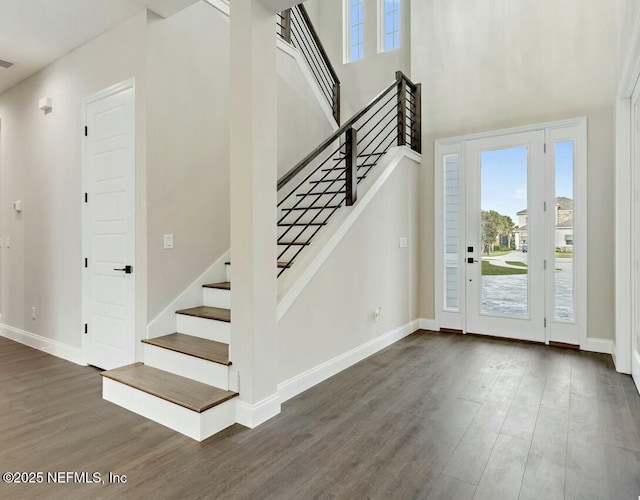 entryway featuring a towering ceiling and dark wood-type flooring