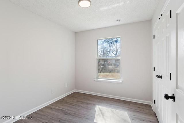 empty room with hardwood / wood-style floors and a textured ceiling