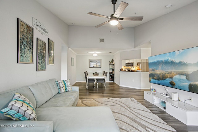 living room with dark hardwood / wood-style floors, ceiling fan, and a high ceiling