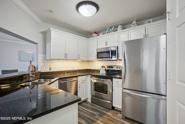 kitchen featuring sink, white cabinetry, tasteful backsplash, ornamental molding, and stainless steel appliances