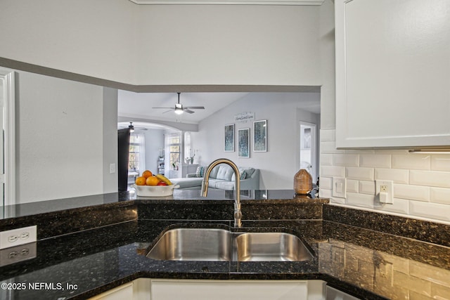 kitchen featuring lofted ceiling, sink, white cabinetry, dark stone counters, and decorative backsplash