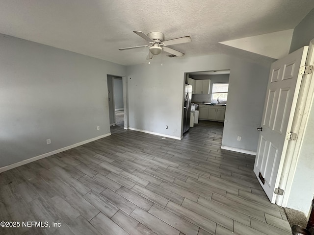 unfurnished room with sink, a textured ceiling, light hardwood / wood-style floors, and ceiling fan