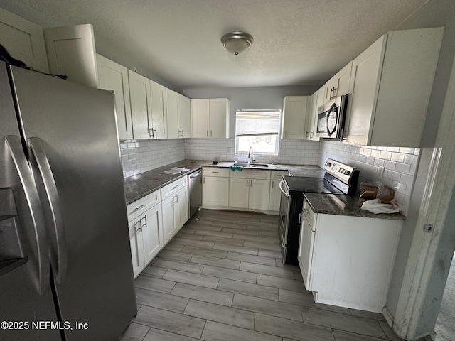 kitchen with tasteful backsplash, appliances with stainless steel finishes, sink, and white cabinets