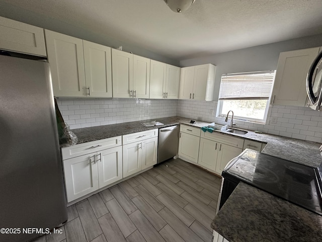 kitchen featuring stainless steel appliances, sink, white cabinets, and backsplash