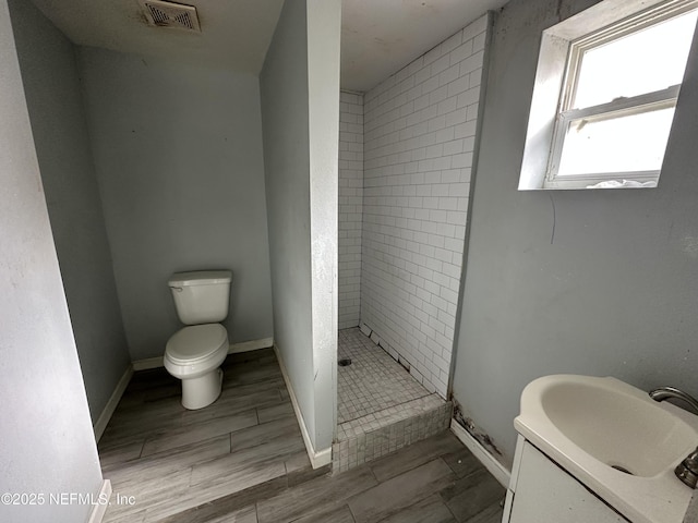 bathroom with vanity, tiled shower, and toilet