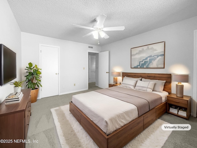 bedroom with ceiling fan, light colored carpet, and a textured ceiling