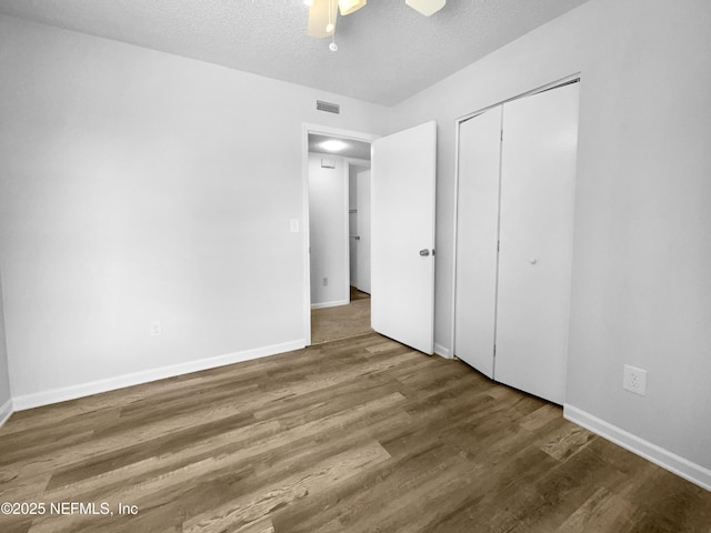 unfurnished bedroom featuring ceiling fan, a closet, hardwood / wood-style floors, and a textured ceiling