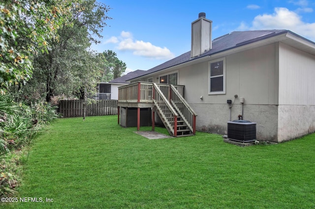 back of property with cooling unit, a wooden deck, and a lawn