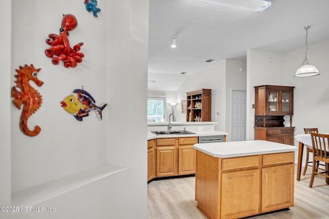 kitchen featuring sink, vaulted ceiling, hanging light fixtures, light hardwood / wood-style flooring, and a kitchen island