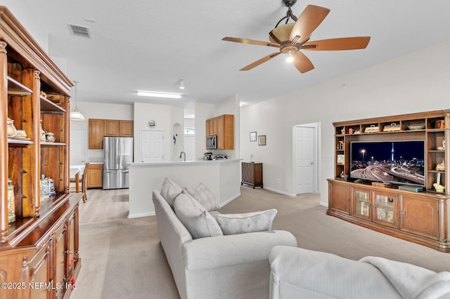 carpeted living room featuring ceiling fan and sink