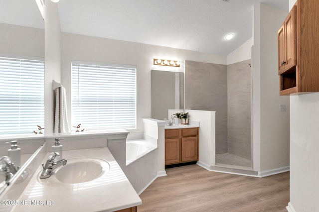 bathroom with vaulted ceiling, vanity, independent shower and bath, and hardwood / wood-style floors