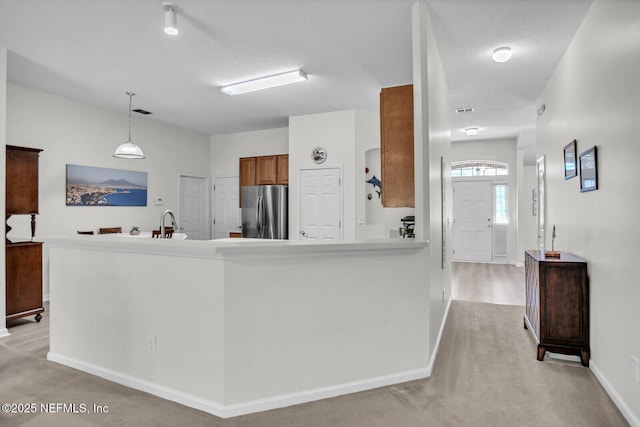 kitchen featuring hanging light fixtures, stainless steel fridge, and kitchen peninsula