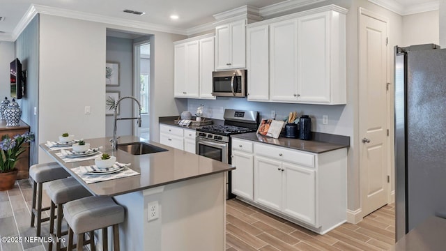 kitchen featuring appliances with stainless steel finishes, sink, a breakfast bar area, white cabinets, and a center island with sink