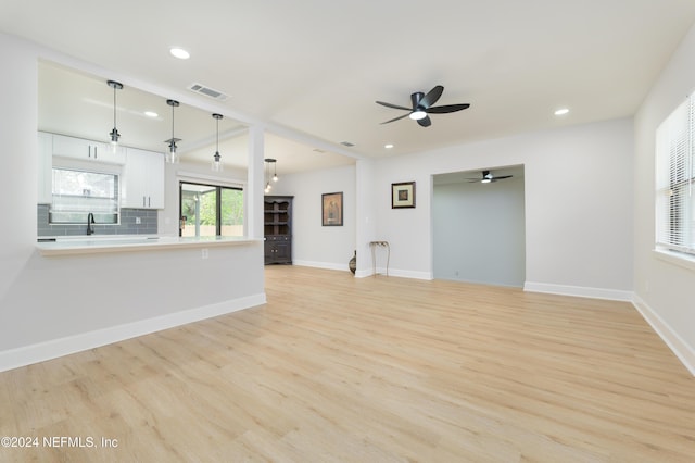 unfurnished living room with ceiling fan, sink, and light hardwood / wood-style flooring