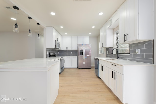 kitchen with sink, appliances with stainless steel finishes, white cabinetry, light hardwood / wood-style floors, and decorative light fixtures