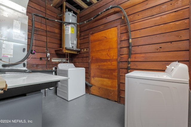 laundry area featuring heating unit, washer and clothes dryer, water heater, and wood walls