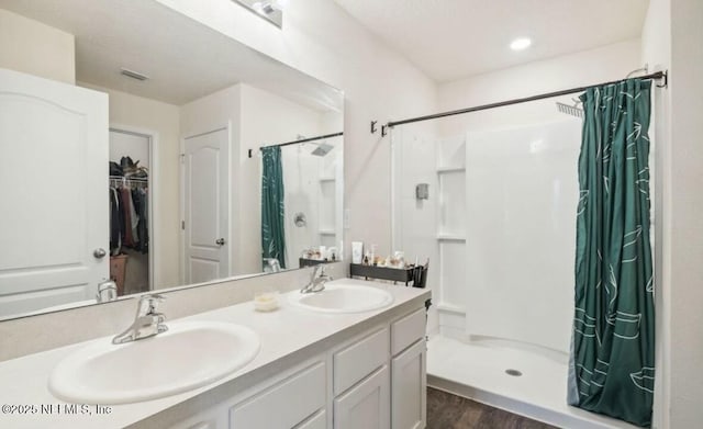 full bathroom with a stall shower, visible vents, a sink, and double vanity