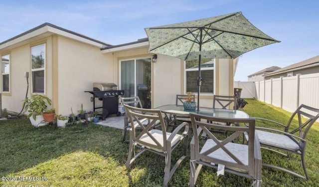 back of property featuring a patio, outdoor dining area, fence, a yard, and stucco siding