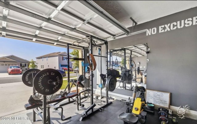 exercise room with a garage and baseboards