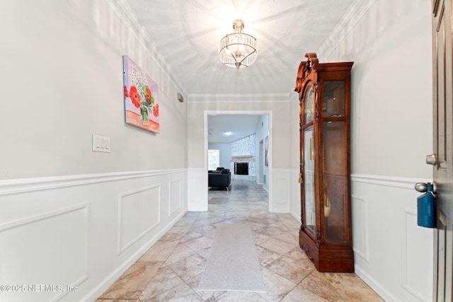 hall featuring ornamental molding, a decorative wall, and an inviting chandelier