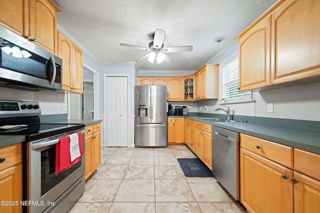 kitchen with stainless steel appliances, dark countertops, crown molding, and a sink