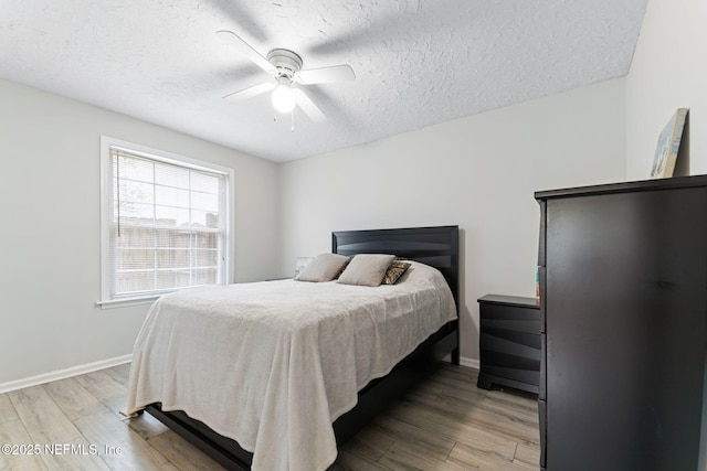 bedroom with a textured ceiling, ceiling fan, wood finished floors, and baseboards