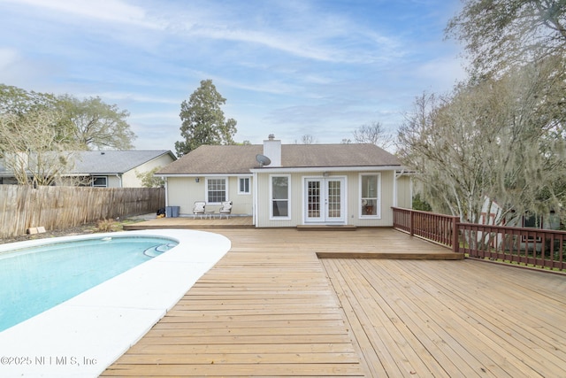 rear view of property featuring fence, a deck, a fenced in pool, and french doors