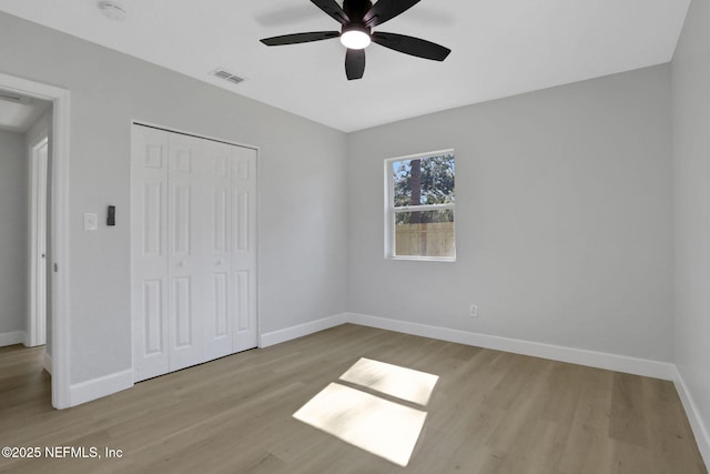 unfurnished bedroom with ceiling fan, light wood-type flooring, and a closet