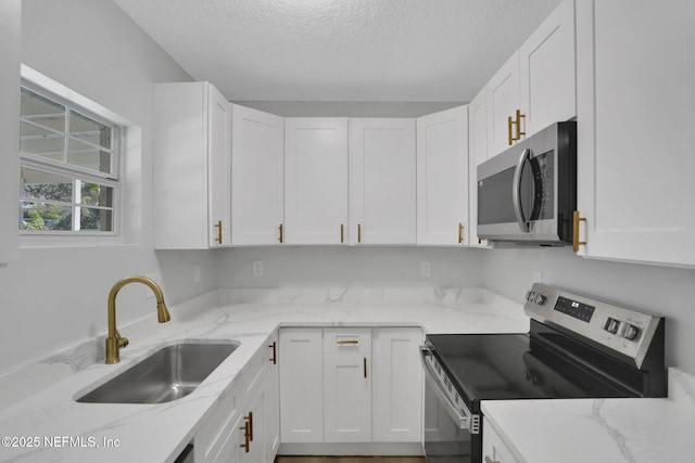 kitchen featuring light stone countertops, white cabinetry, appliances with stainless steel finishes, and sink