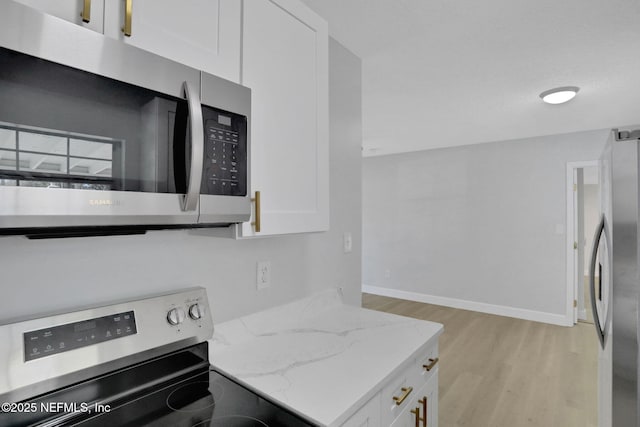 kitchen featuring white cabinetry, stainless steel appliances, light stone countertops, and light hardwood / wood-style flooring