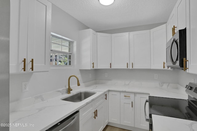 kitchen with white cabinetry, sink, light stone counters, and appliances with stainless steel finishes