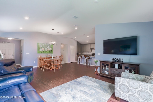 living room with dark hardwood / wood-style floors, a chandelier, and vaulted ceiling