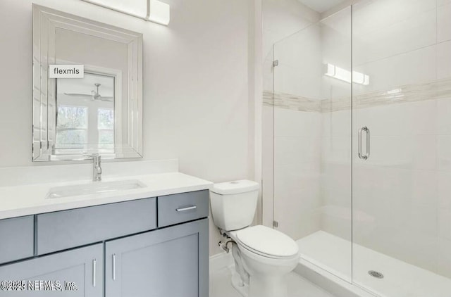 bathroom featuring vanity, a shower with door, and toilet