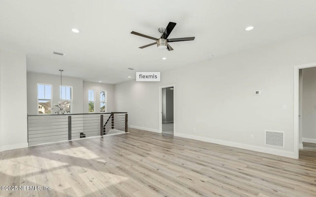 empty room with ceiling fan and light hardwood / wood-style flooring