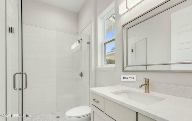 bathroom with walk in shower, vanity, and toilet