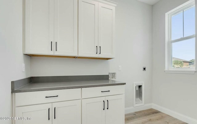 clothes washing area featuring cabinets, hookup for an electric dryer, and light hardwood / wood-style floors